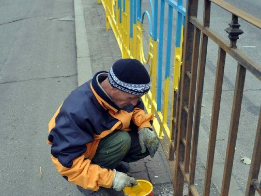 В Запорожье активист красит ограждение вдоль проспекта в сине-желтые цвета